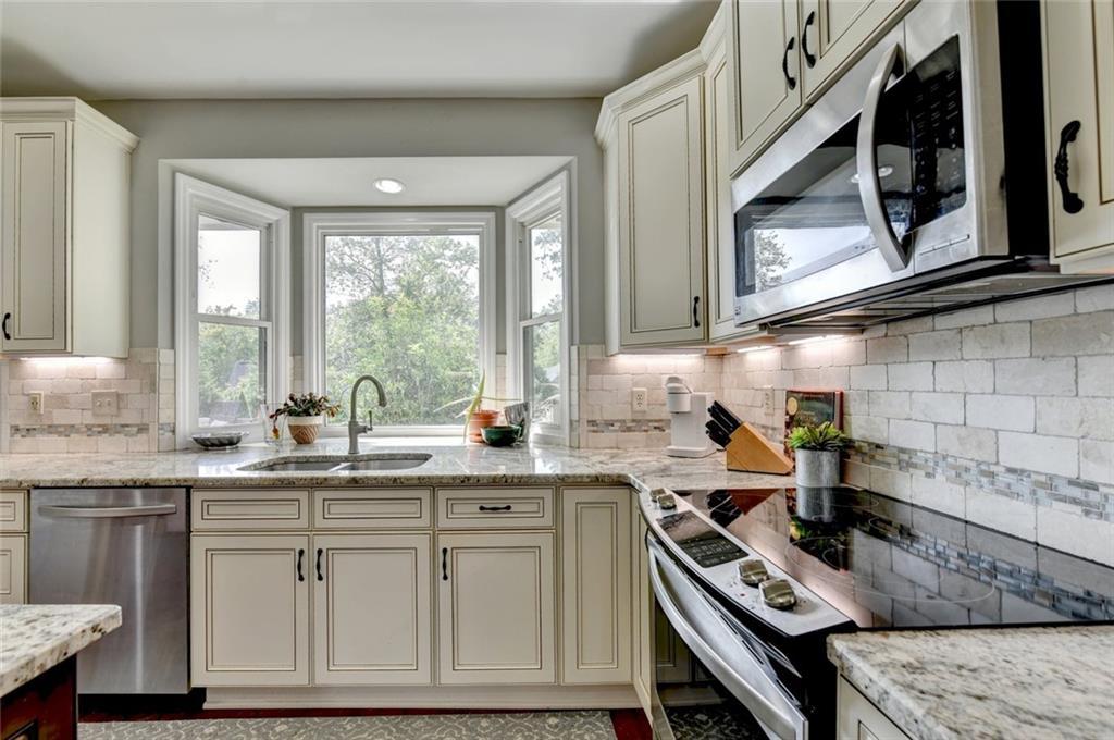 Kitchen with white cabinets, stone counters and a bay window over the sink
